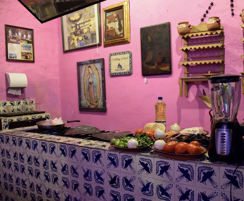Cocina de la escuela de cocina tradicional poblana en Mesones Sacristía, Puebla, con azulejos de talavera e ingredientes frescos